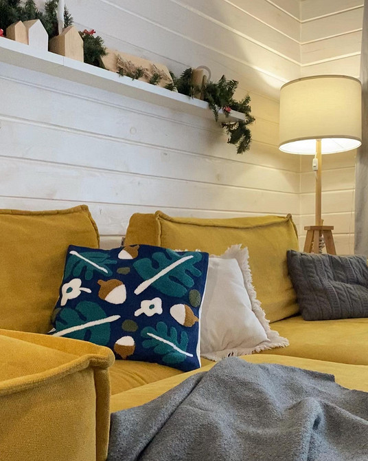 Інтер'єр вітальні з жовтим диваном, каміном та декоративними подушками різних кольорів