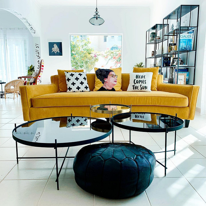 Дизайн інтер'єру з жовтим диваном, книжковою шафою та рослинами у горщиках.