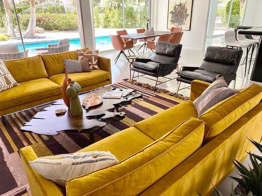 Жовтий кутовий диван у просторій вітальні з великими вікнами