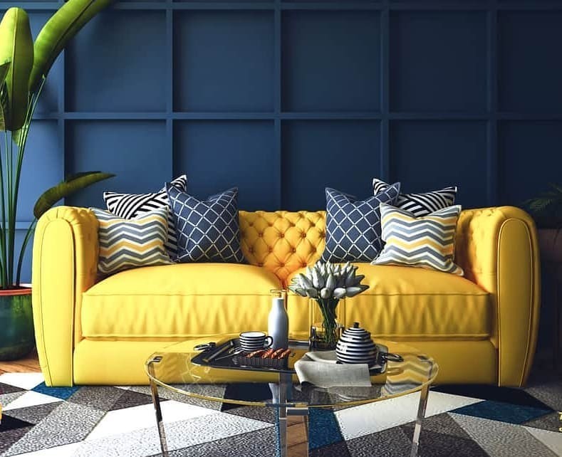 Жовтий диван з подушками різних кольорів в інтер'єрі з білими стінами.