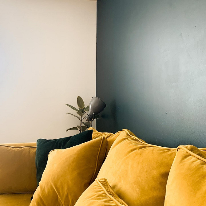 Жовтий кутовий диван у вітальні з великим вікном та видом на місто