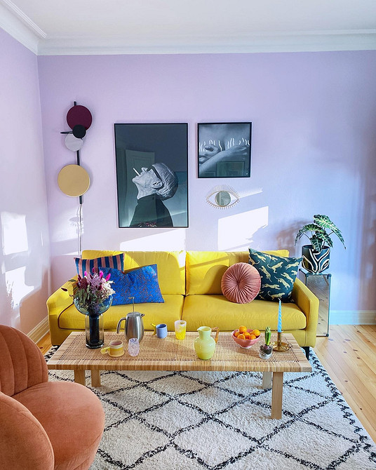 Жовтий диван у скандинавському стилі з дерев'яними ніжками та світлим текстилем в інтер'єрі.