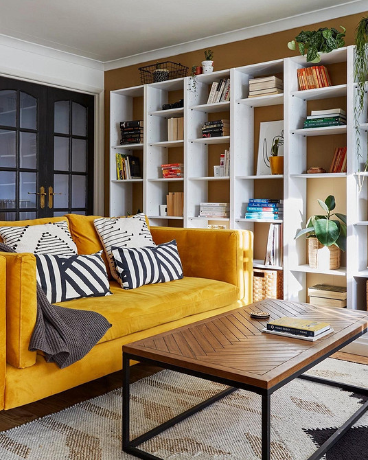 Жовтий диван в сучасному інтер'єрі вітальні з яскравими акцентами