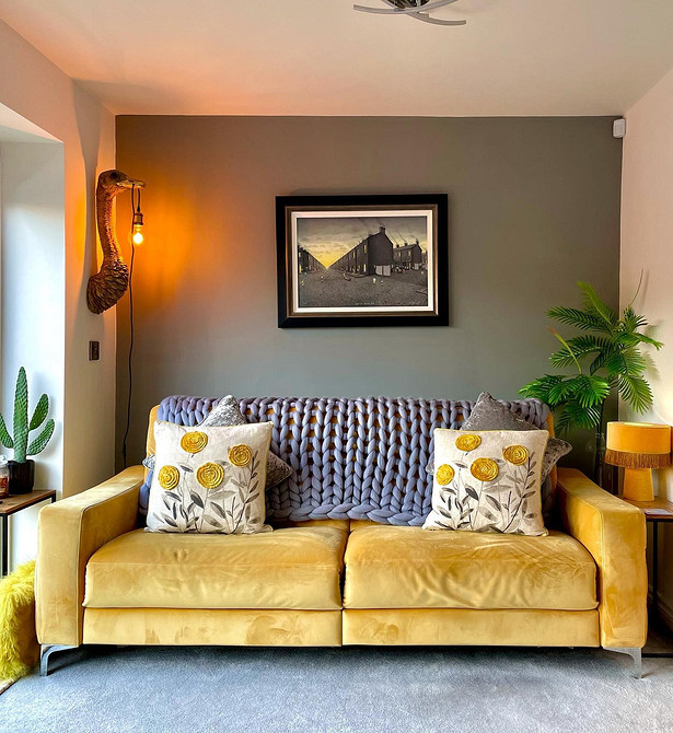 Жовтий диван в інтер'єрі вітальні з сірими стінами та дерев'яною підлогою