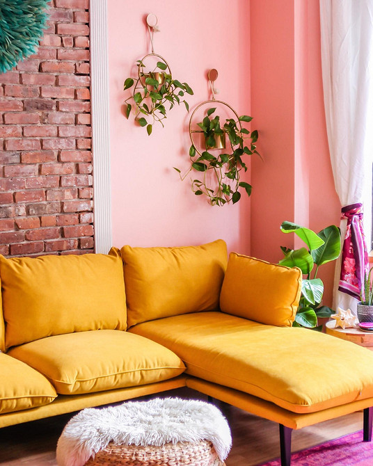 Жовтий велюровий диван в інтер'єрі з книжковими полицями та торшером.