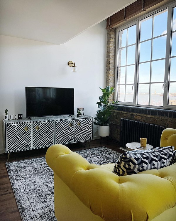 Жовтий диван в інтер'єрі з бежевими стінами та синіми акцентами для стильного дизайну.