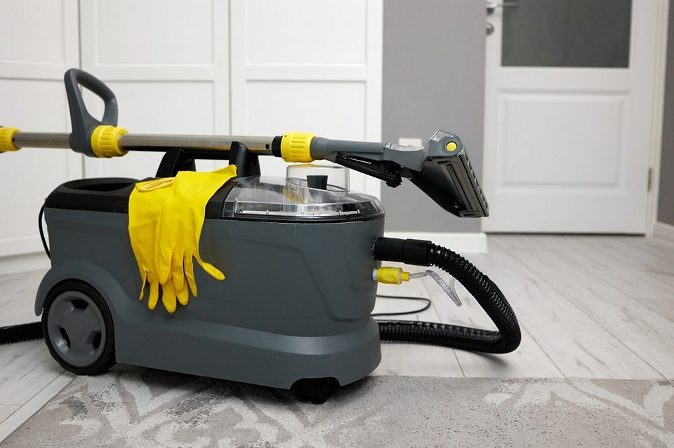 Жінка використовує миючий пилосос для чистки килима від плям в квартирі.