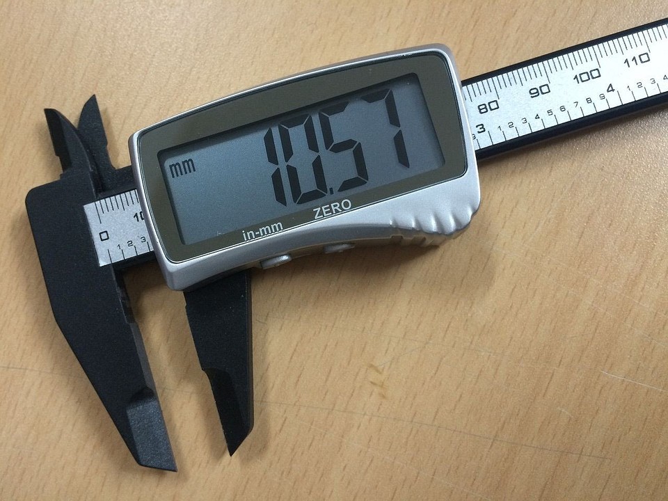 Рука тримає штангенциркуль для вимірювання глибини отвору; демонстрація процесу вимірювання.