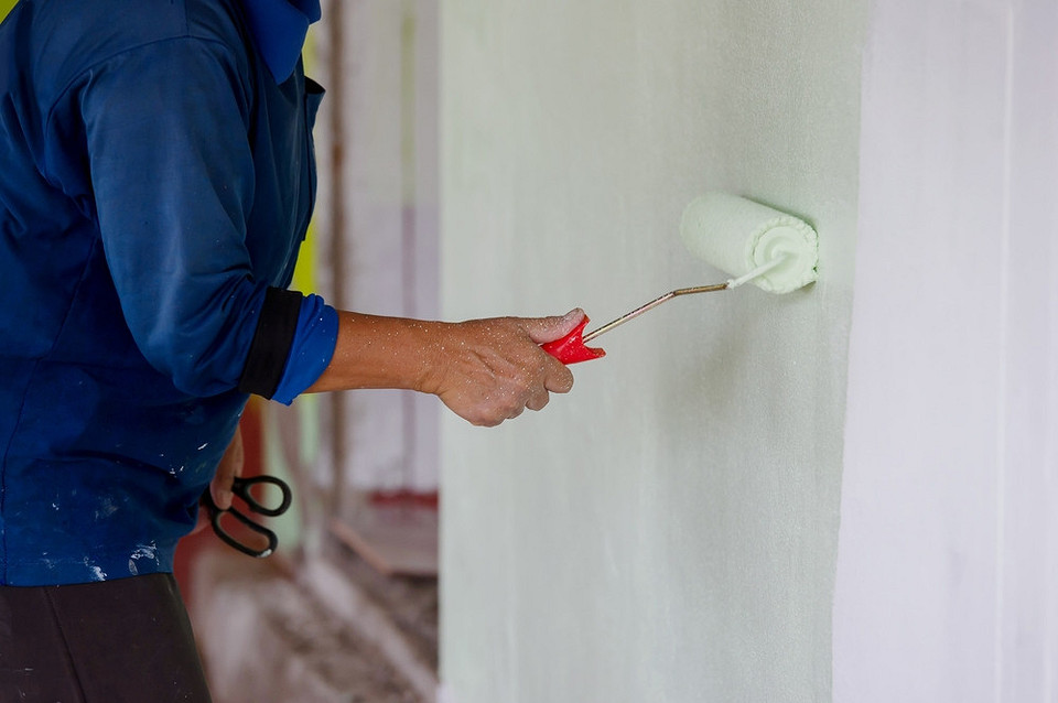 Фарбуємо самі! Жінка фарбує стіну валиком, використовуючи правильну техніку для досягнення ідеального результату.
