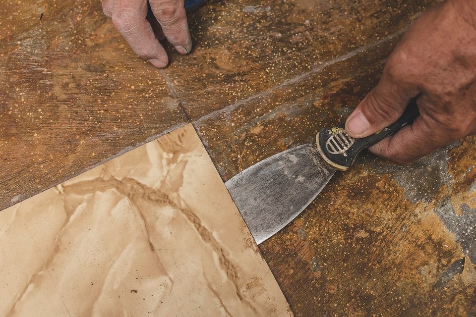 Акуратно знімаємо плитку Процес відділення плитки від стіни за допомогою шпателя.