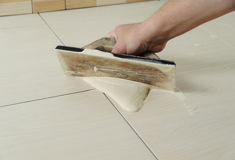 Заповнення плиткових швів Процес заповнення швів між плитками цементною затиркою.