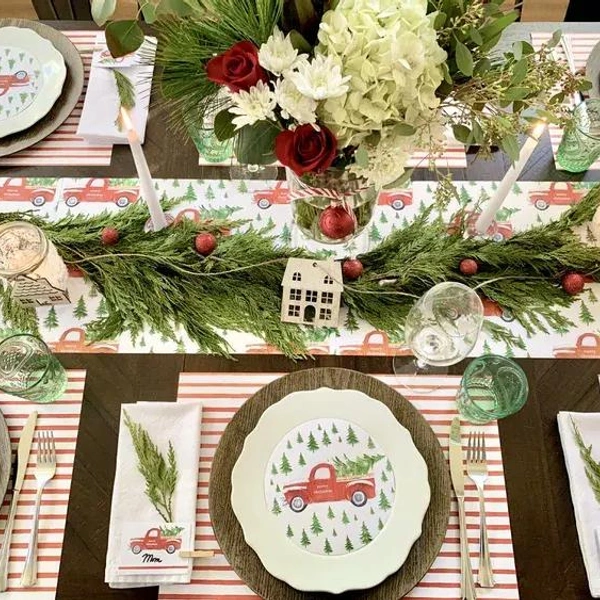 Свіжість та свято Новорічне сервірування столу 2026: зелені ялинкові гілки та червоні келихи.