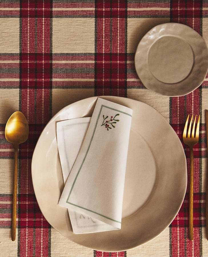 Затишні вогні Святкове сервірування новорічного столу 2026: червоні свічки та зелені серветки.