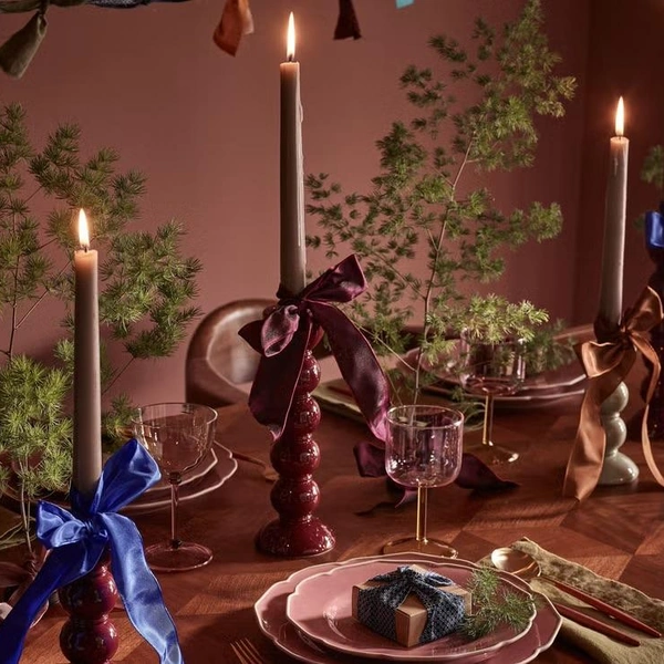 Золоті новорічні штрихи Деталі сервірування новорічного столу 2026: блискучі золоті акценти та зелені гілки.