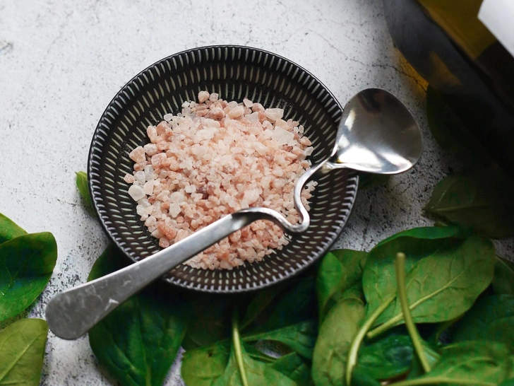 Збір розсипаної солі Жіноча рука обережно збирає розсипану сіль з поверхні, що символізує очисні обряди.